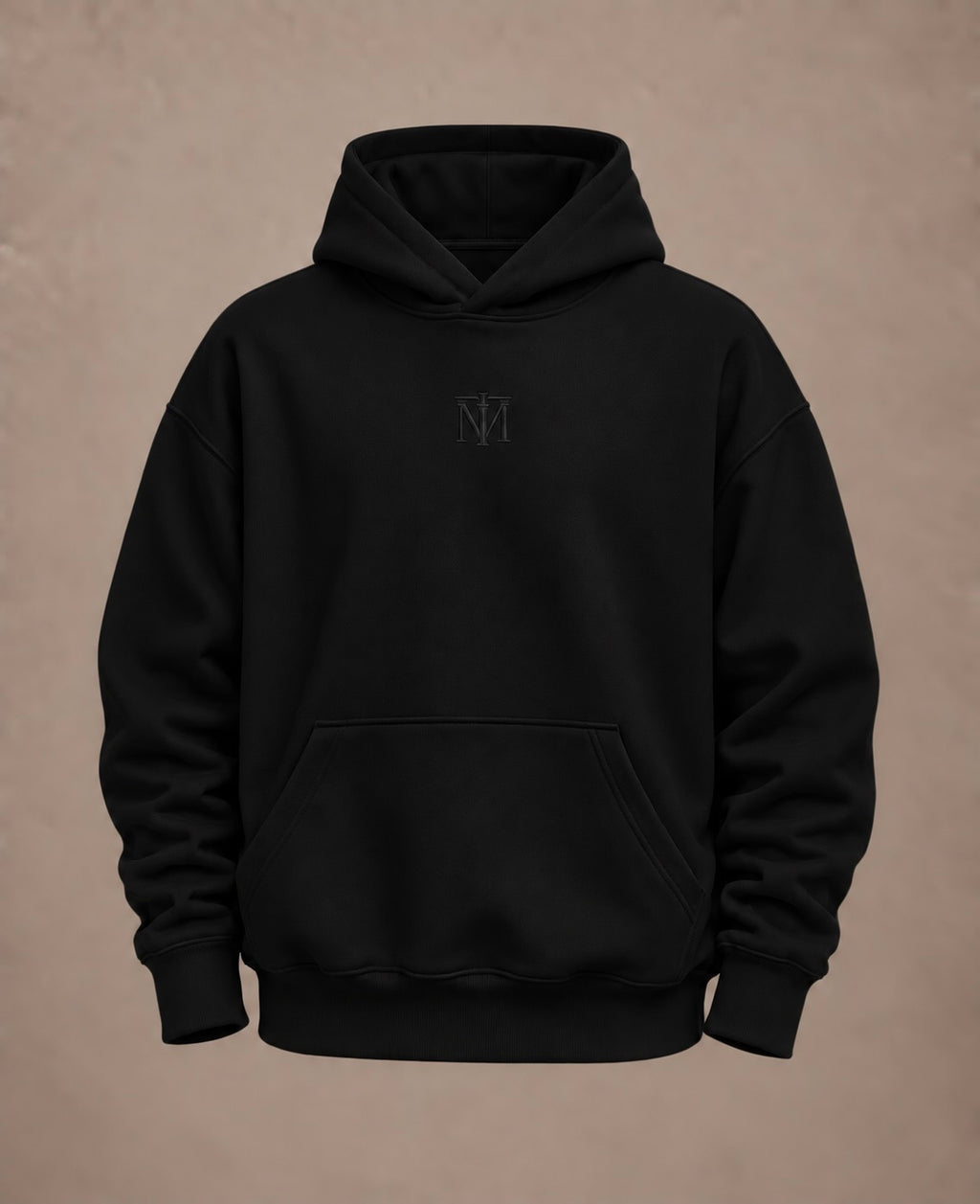A black pullover hoodie with a small tonal embroidered 'NM' logo on the center chest, displayed against a textured warm brown background.